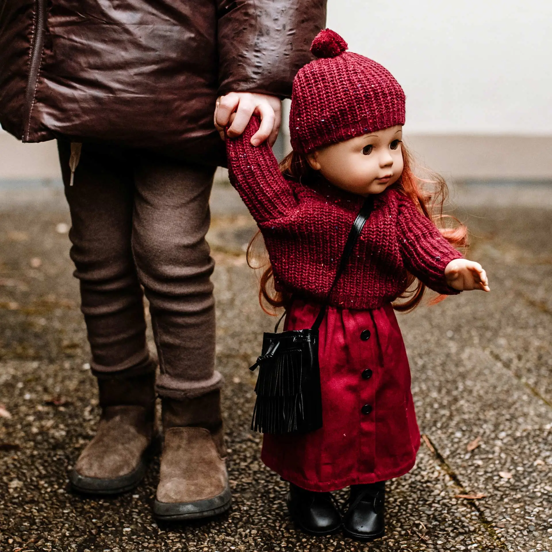 Kind haelt die Hand einer 46 cm großen Stehpuppe mit braunen Schlafaugen die Hand
