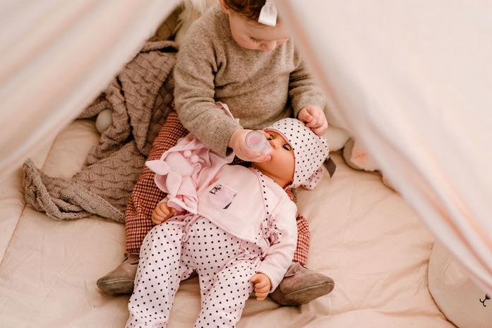 Babypuppe Cookie wird von Kind mit dem Flaeaschchen gefüttert