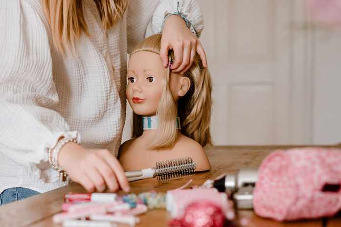 Kind frisiert und schminkt blonden Frisierkopf