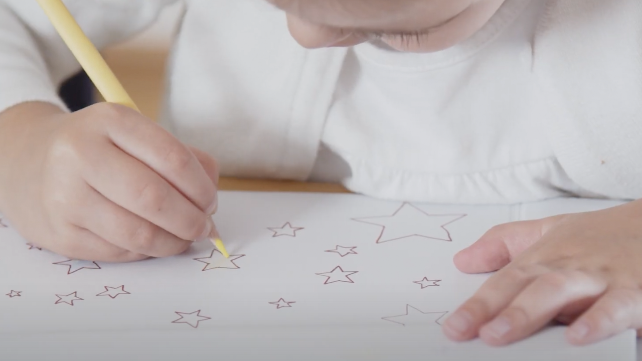 Kind malt Sterne mit einem gelben Bundstift aus