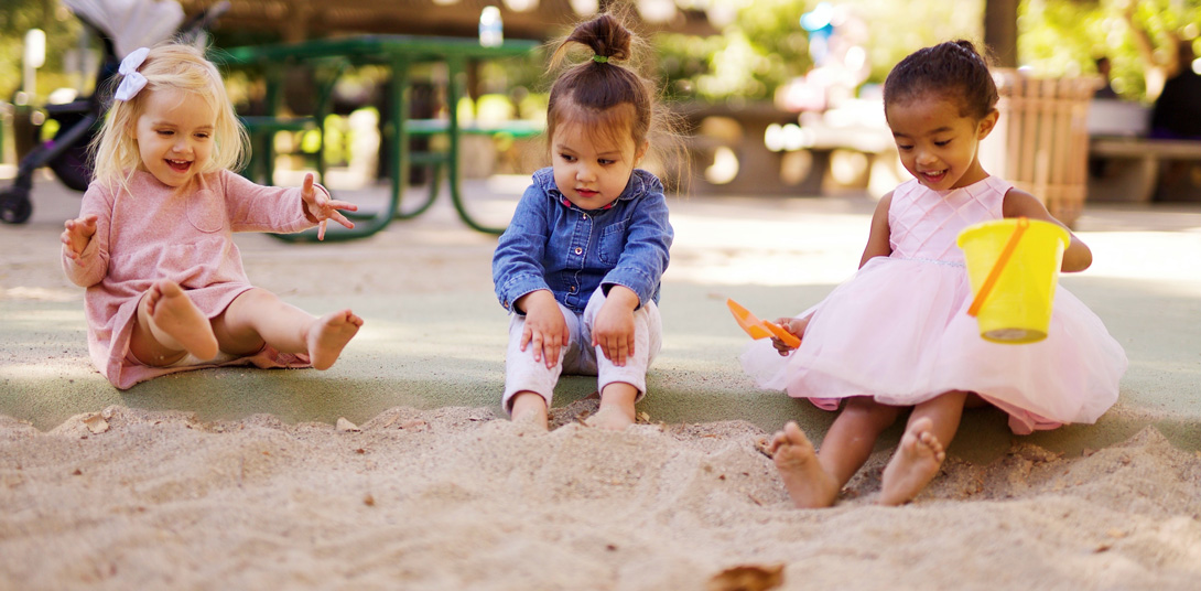 Kinder sitzen im Sandkasten und spielen 