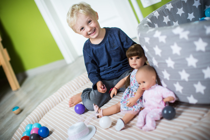Kind spielt im Kinderzimmer mit Götz Babypuppe und Götz Stehpuppe