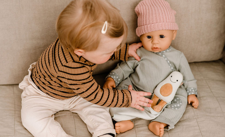 kreatives-spielen-goetz-puppen-kind-babypuppe-bild Kind und Puppe sitzen im Laub