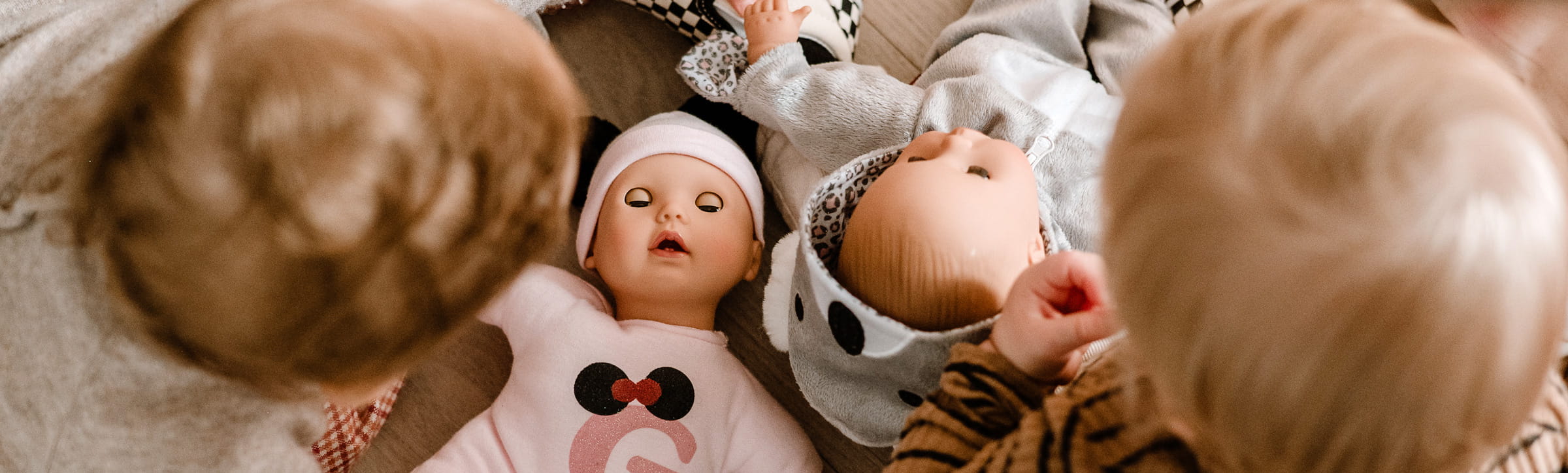 Zwei Kinder spielen mit babypuppen von Goetz auf dem Boden