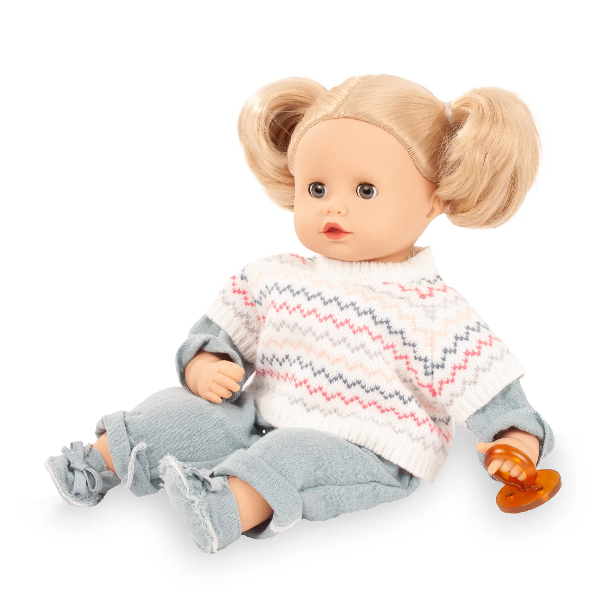 Babypuppe Gr. 33 cm mit blondem Haar und blauen Schlafaugen. Sie hat einen Schnuller dabei, traegt einen Overall mit Strickpullunder darüber und Stoffschuhe von Goetz
