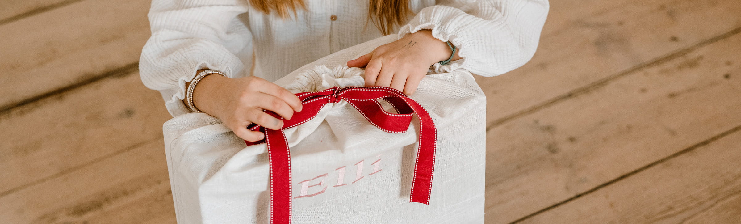 Sinnvolle Geschenke zum Geburtstag Goetz Kind oeffnet Geschenkbeutel mit roter Schleife