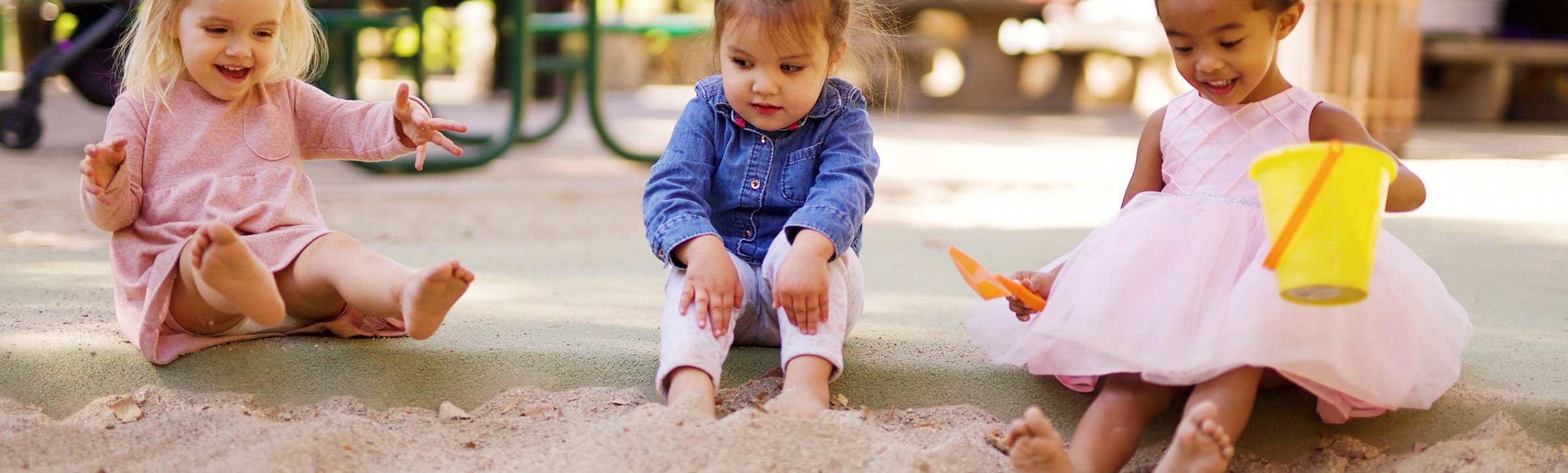 Kinder spielen in einem Sandkasten und haben Spaß mit Puppen