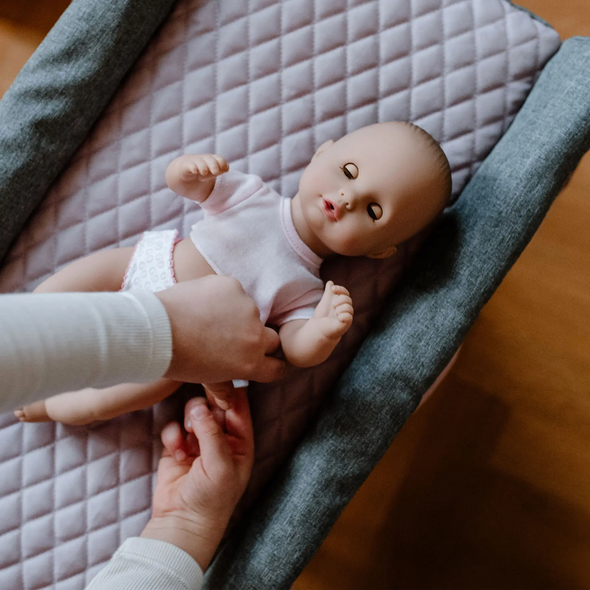 Kind wickelt eine 33 cm grosse Babypuppe mit Schlafaugen auf einem Wickeltisch