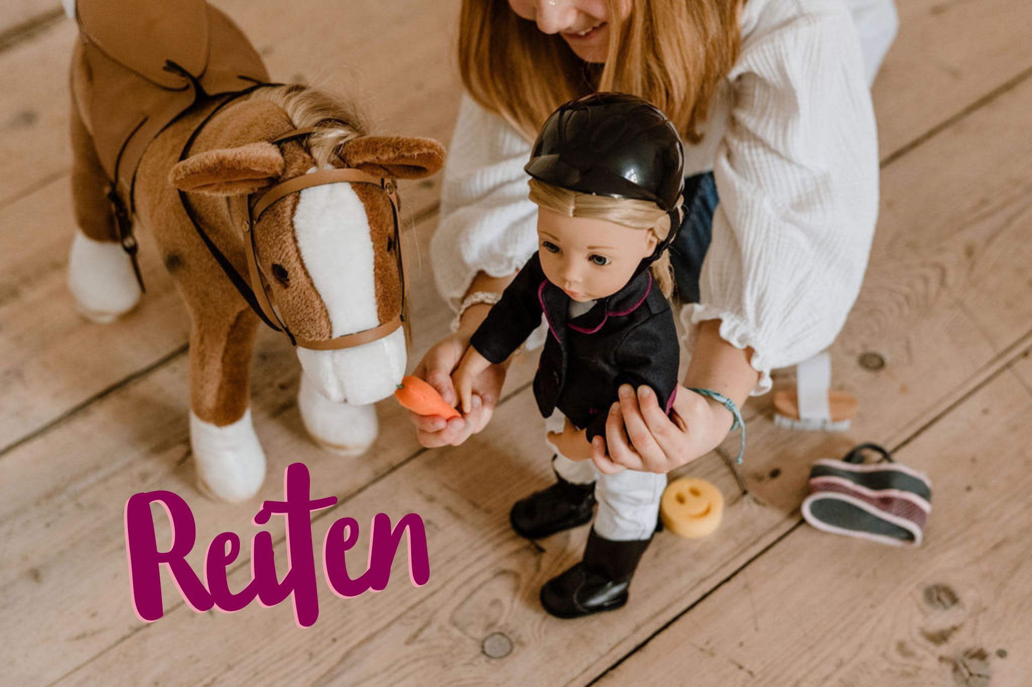 Kind spielt mit einer 50 cm grosser Stehpuppe mit blonden Haaren im Reiteroutfit und fuettert das Plueschpferd mit einer Karotte