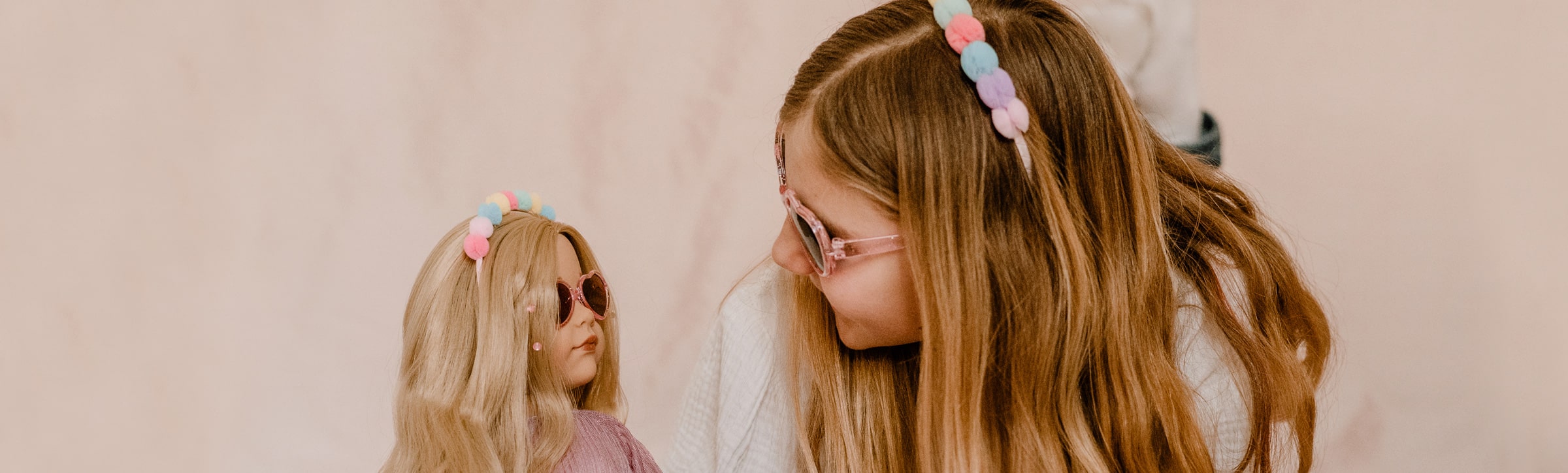 Hannah Be My Mini Me Goetz Kind und blonde Stehpuppe tragen im Partnerlook den gleichen Haarreif und die gleiche Sonnenbrille und schauen sich an