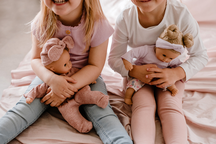 Kinder halten Babypuppen im Arm und lachen