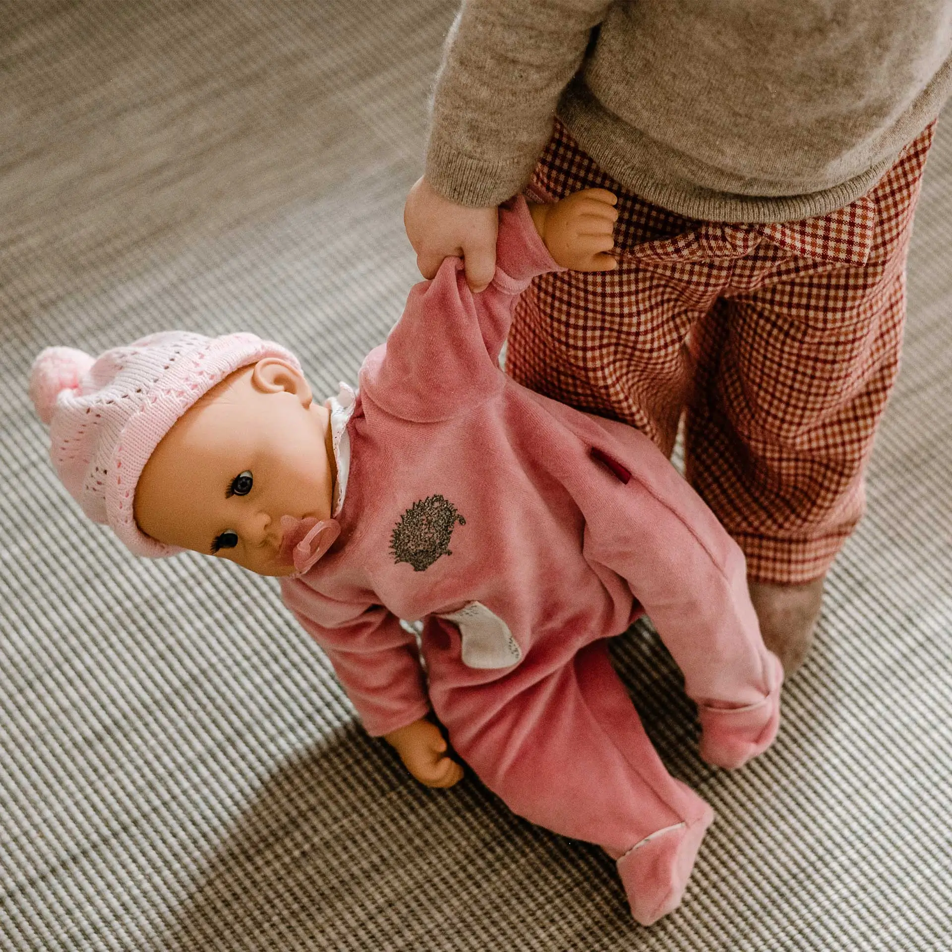 Kind haelt 48 cm große Babypuppe mit Schlafaugen und Schnuller und rosa Strampler