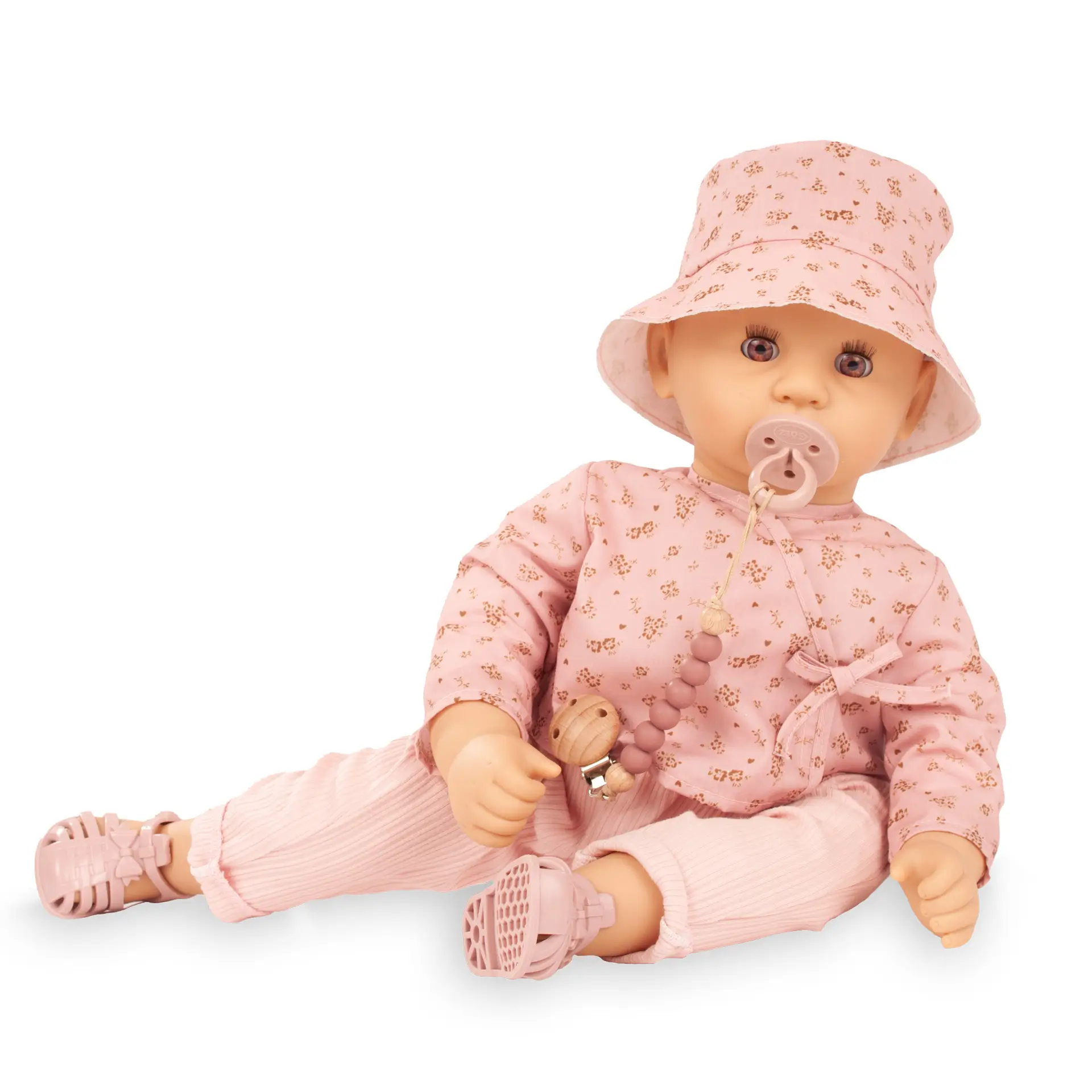 Babypuppe Gr. 48 cm mit braunen Schlafaugen in hellrosa Anzug mit Bluemchen, einem angarmshirt, Hose, Cappy und Badesandalen, dazu ein Schnuller mit Schnullerkette von Goetz