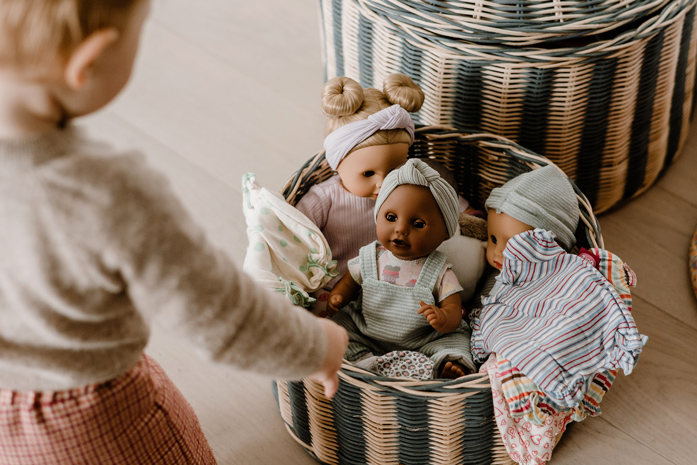 Kind spielt mit Puppen im Korb