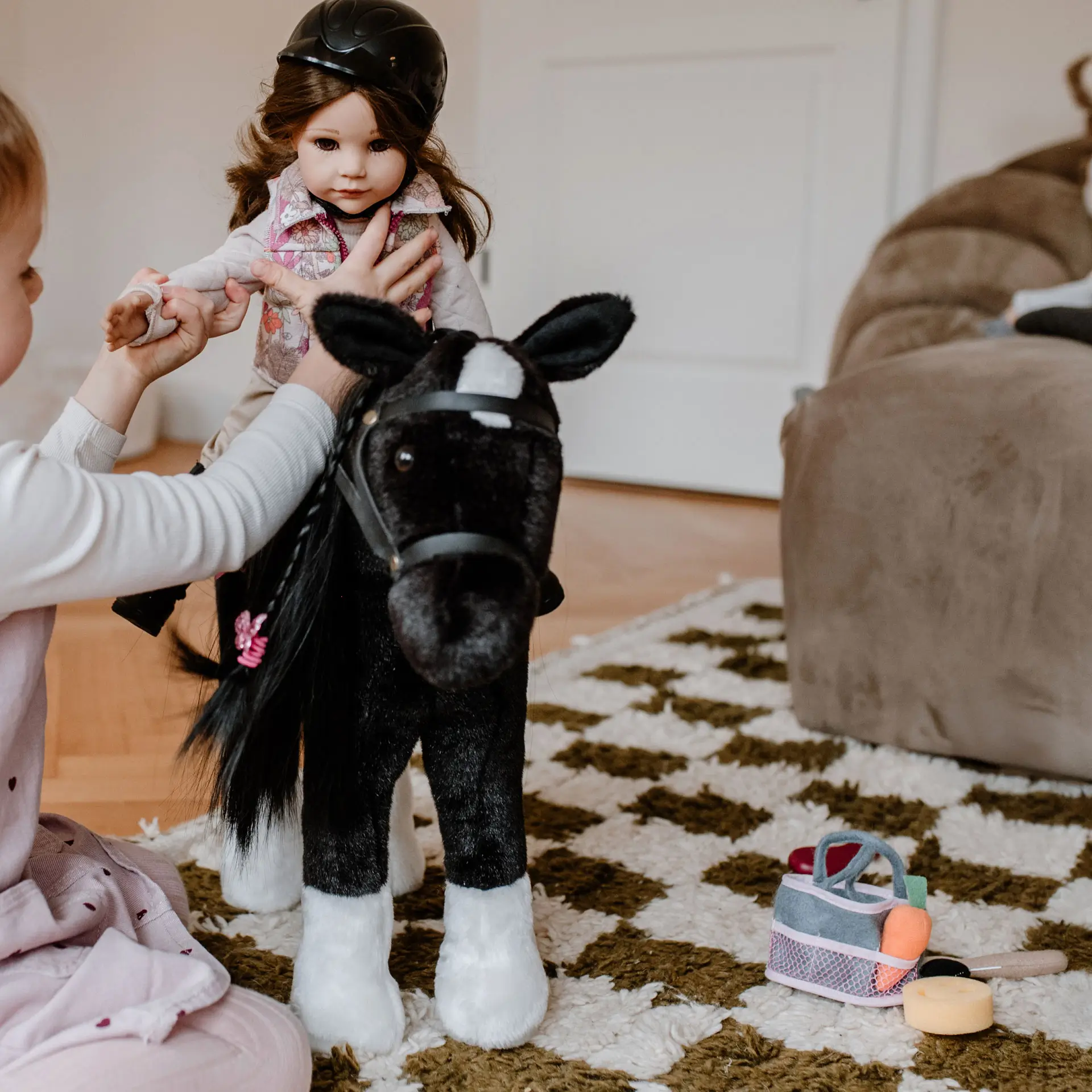 Kind setzt 50 cm grosse Reiterpuppe mit braunen Haaren auf schwarzes Plueschpferd