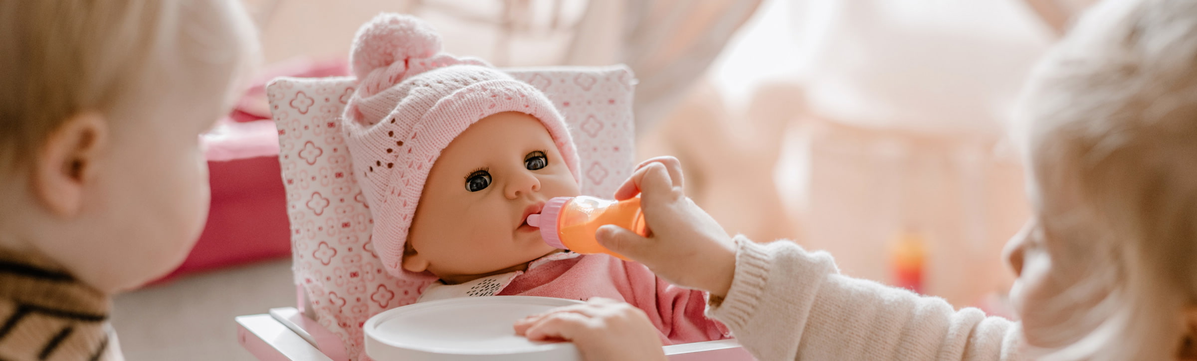 Kind fuettert Babypuppe mit Trinkflasche
