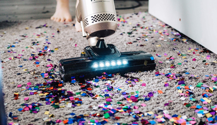 Teppich mit buntem Konfetti wird gestaubsaugt