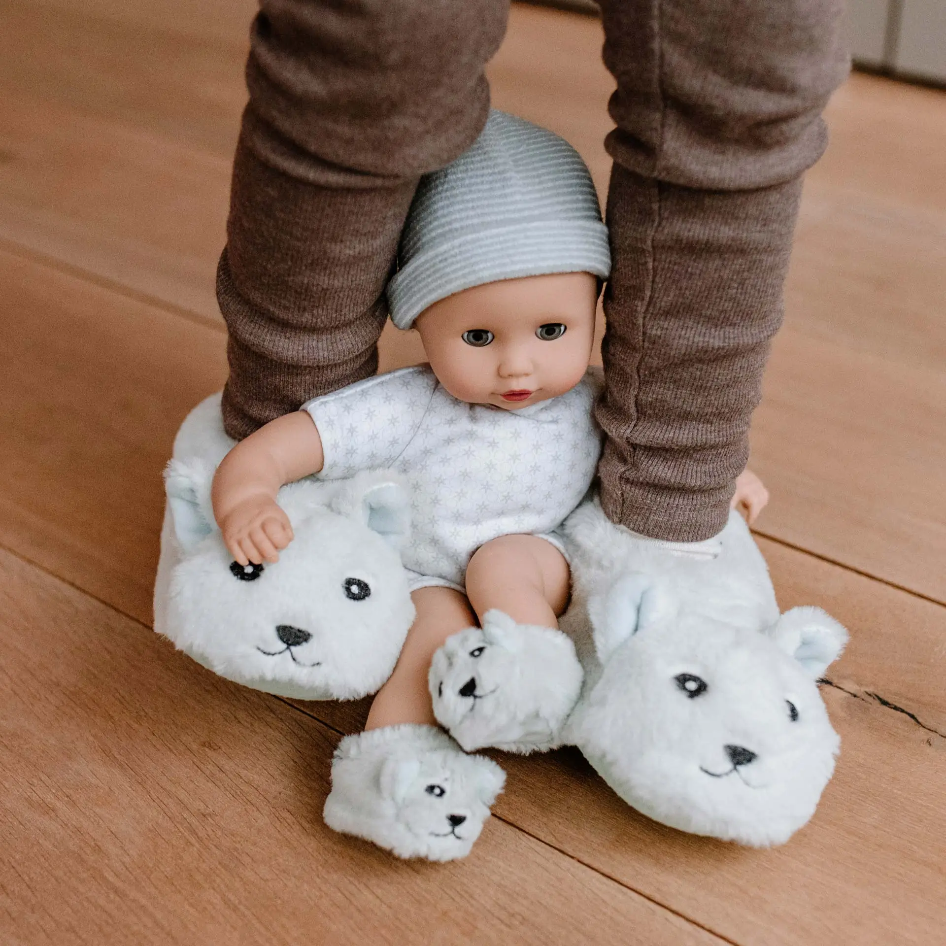 33 cm große Babypuppe mit blauen Schlafaugen und blauer Muetze sitzt zwischen den Beinen