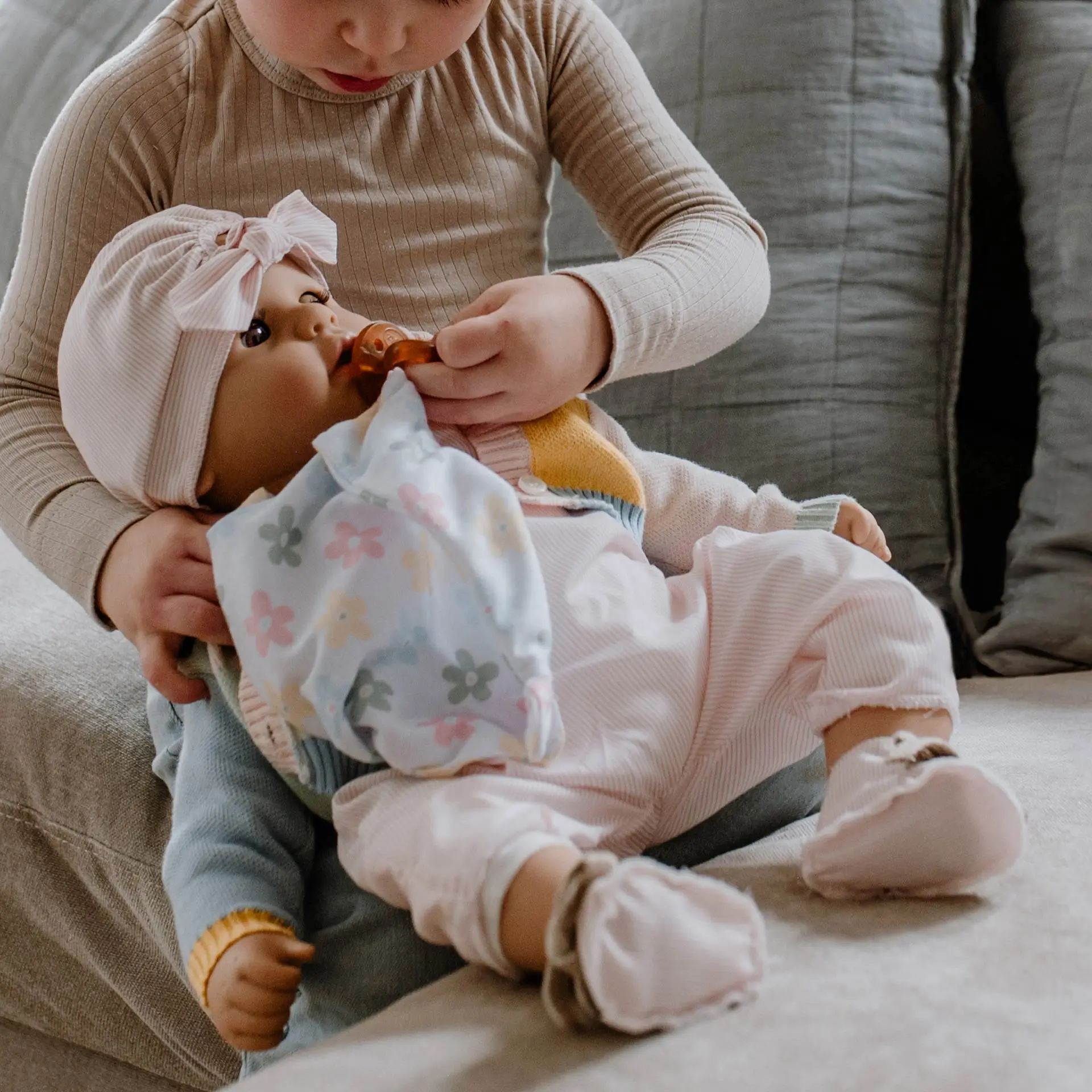 2461054 Cookie Farbspiel Goetz Kind gibt einer 48 cm grossen Babypuppe mit Schlafaugen einen Schnuller