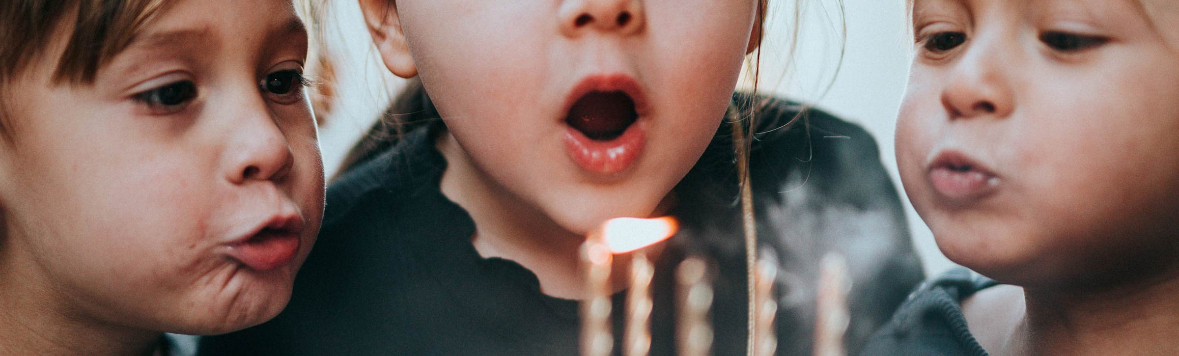 Kinder pusten eine Kerze aus und feiern ihren Kindergeburtstag