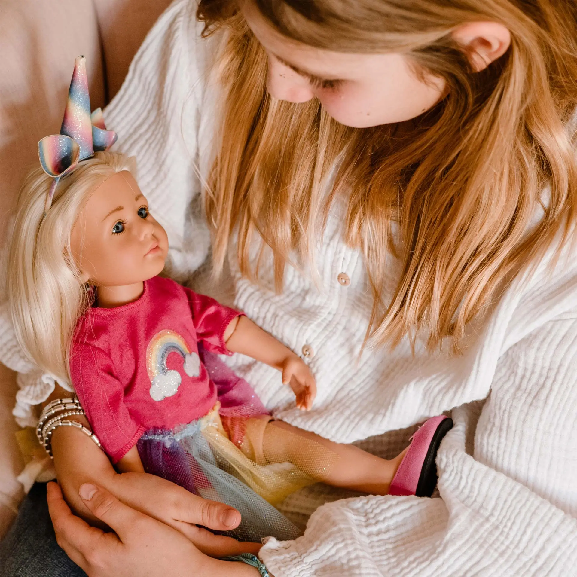 Kind haelt eine 36 cm große blonde Stehpuppe mit einem Einhornkostuem in den Armen