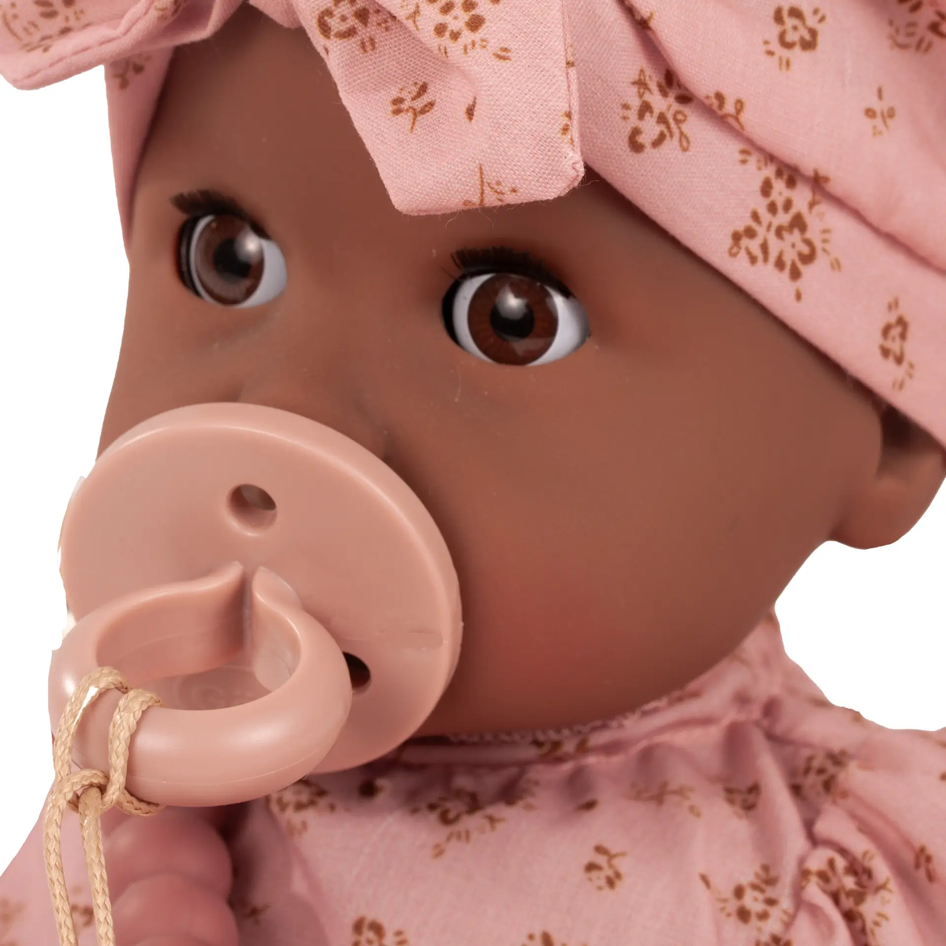 Portrait von brauner Badepuppe Gr. 33 cm mit braunen Schlafaugen ohne Haare und einer Muetze in rosa mit goldfarbenen Bluemchen und einem Schnuller von Goetz