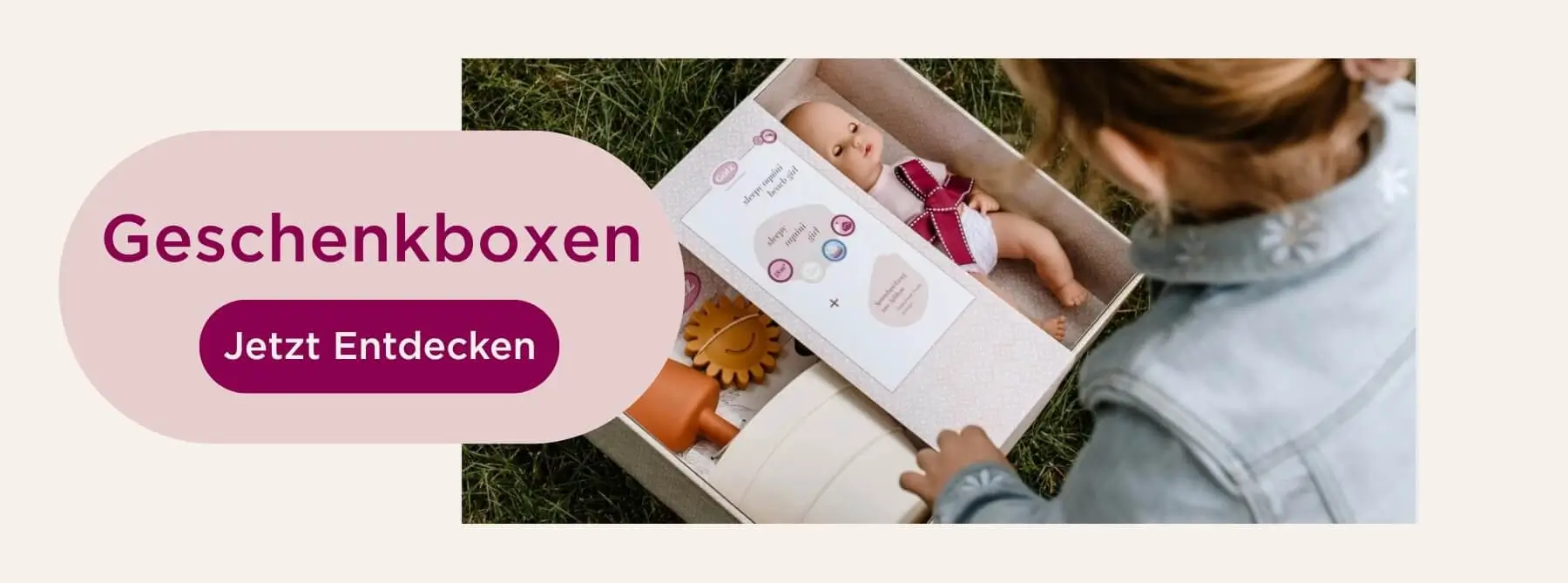 Kind oeffnet eine Geschenkbox mit Puppe und Puppenzubehoer, liebevoll arrangiert als Geschenkidee