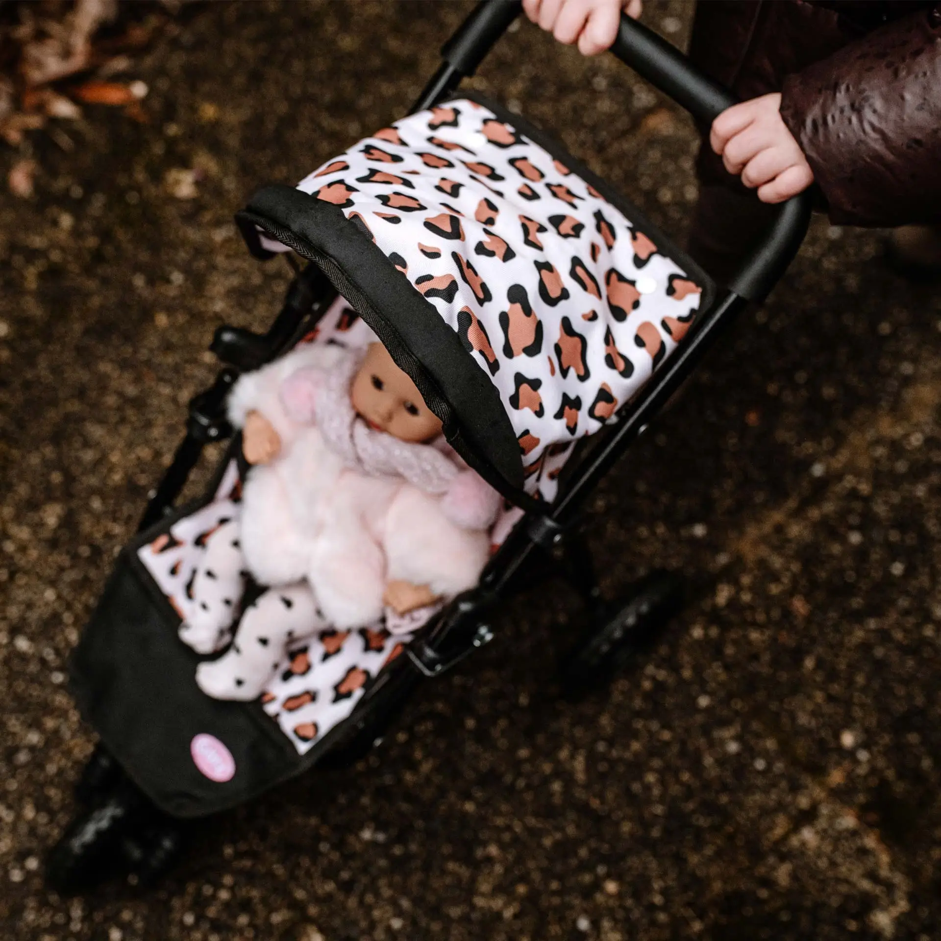 Kind schiebt Puppenbuggy in Tigermuster und darin sitzt eine 33 cm große Babypuppe