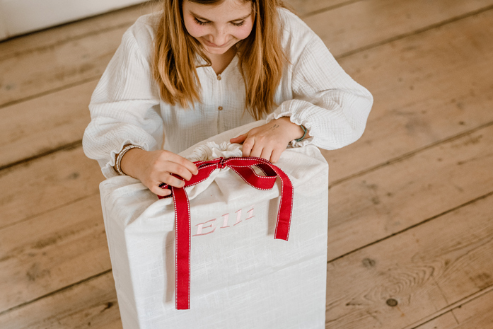 Kind oeffnet Geschenkbeutel mit roter Schleife