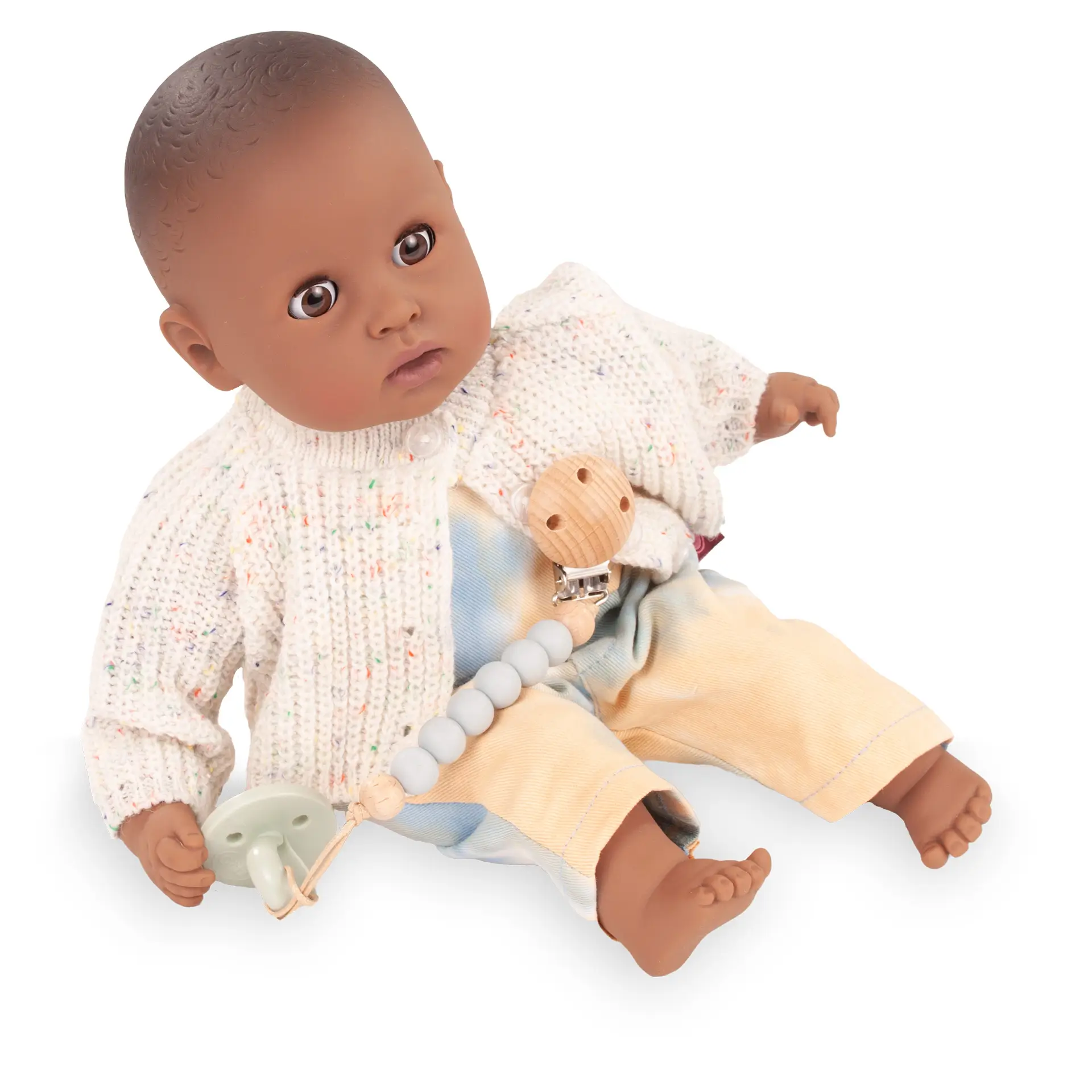 Bekleidungsset Gr. 30-33 cm, bestehend aus einer Latzhose im Batiklook mit Strickjacke und einer Schnullerkette mit Schnuller, angezogen. Von Goetz