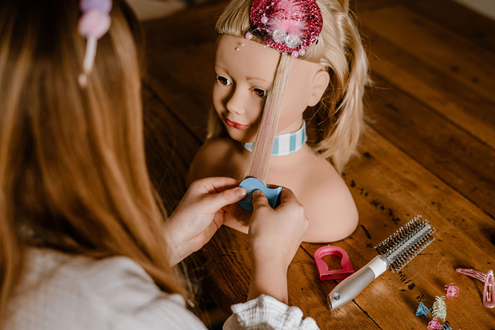 Kind frisiert und schminkt blonden Frisierkopf