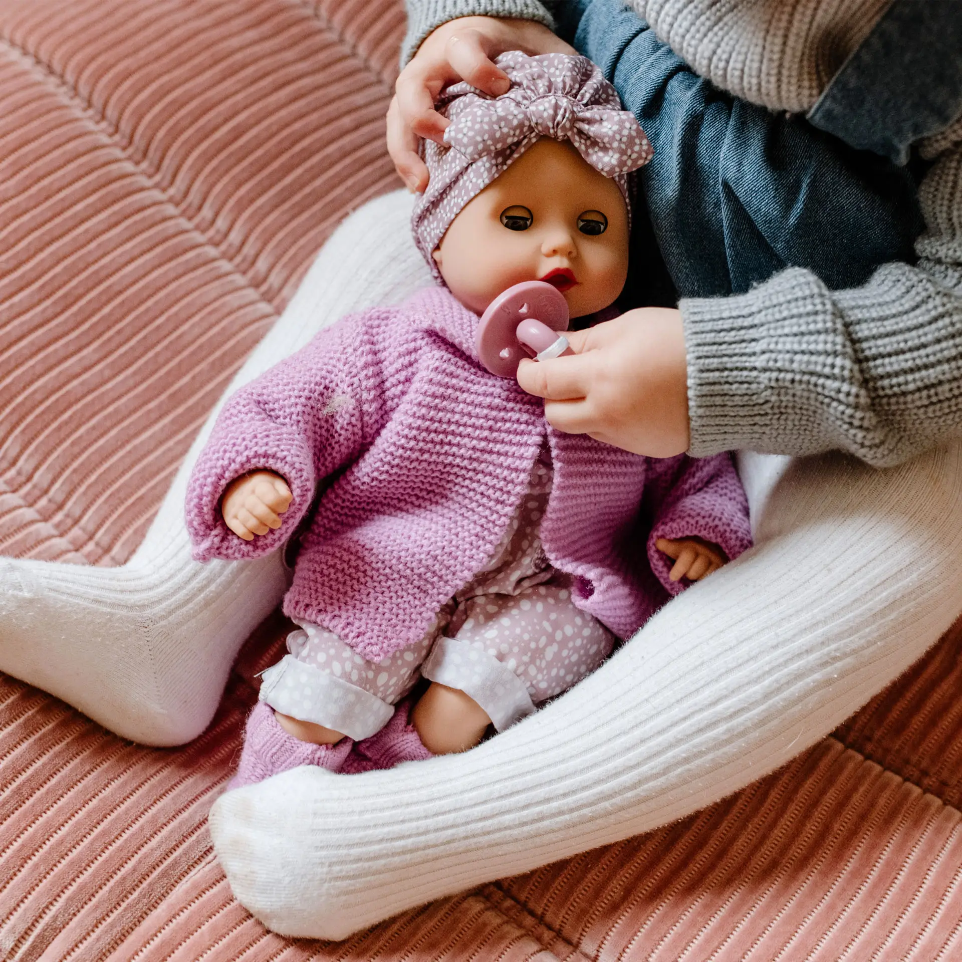 Kind gibt 33 cm grosser Babypuppe mit Schlafaugen einen Schnuller