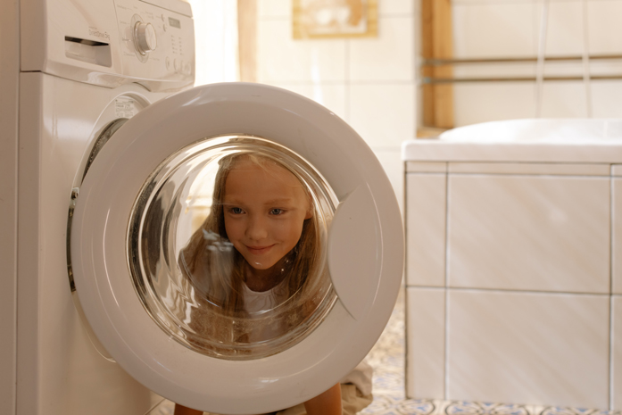 Kind steht an der Waschmaschine