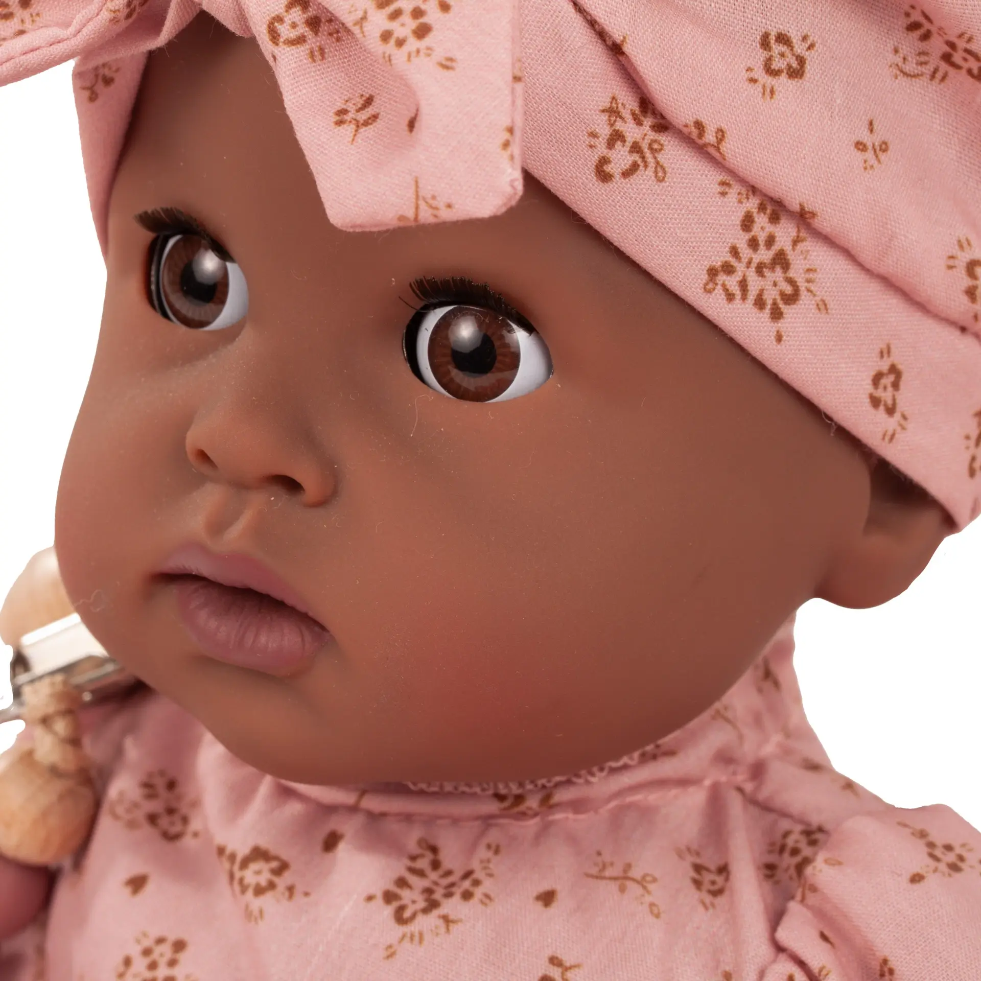 Portrait von brauner Badepuppe Gr. 33 cm mit braunen Schlafaugen ohne Haare und einer Muetze in rosa mit goldfarbenen Bluemchen von Goetz