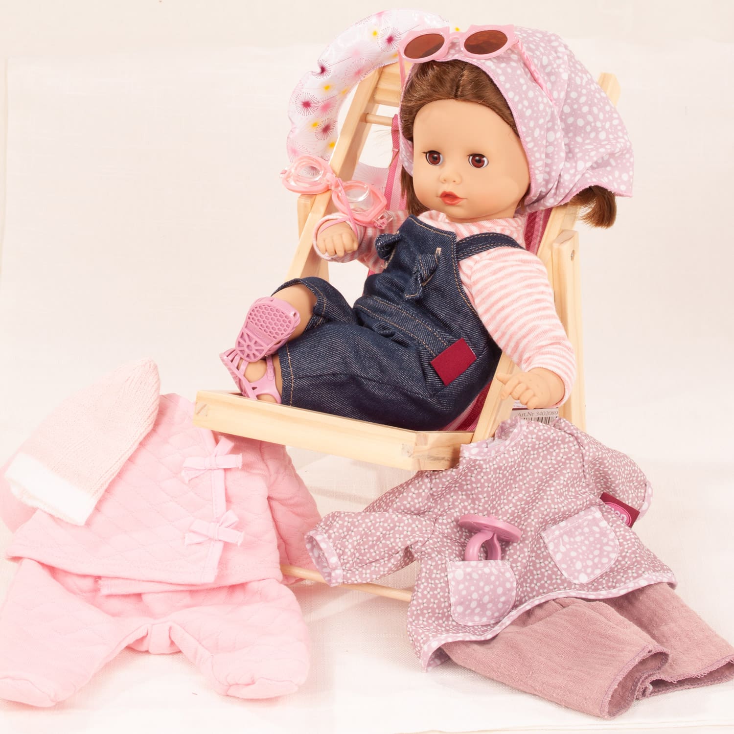 33 cm grosse Babypuppe mit braunen Haaren und Schlafaugen, mit Sonnenbrille, Taucherbrille, Liegestuhl, Latzhose, Sandalen, Kopfbedeckung und Winteranzug