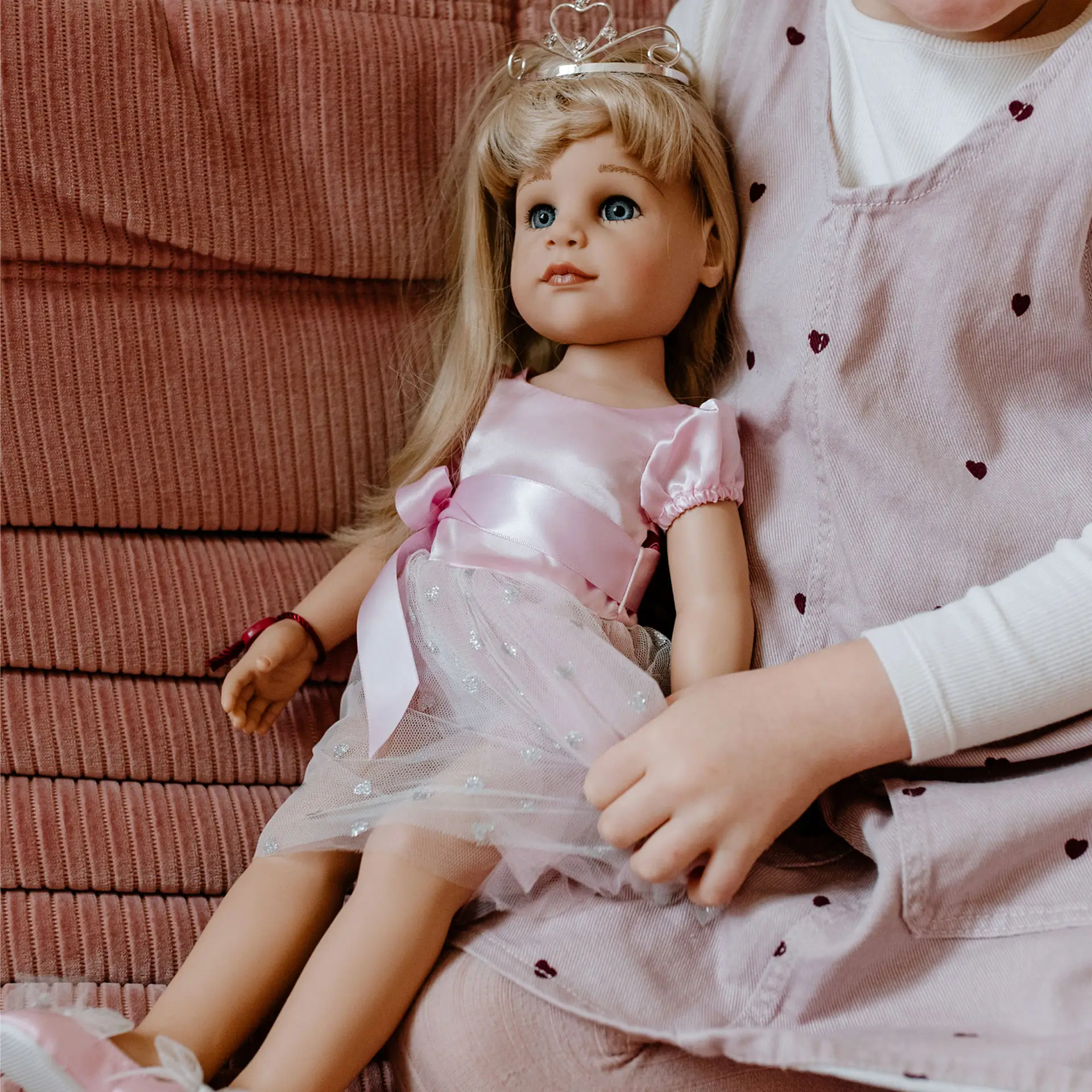 Kind spielt mit 50 cm grosser Stehpuppe mit blonden Haaren im Prinzessinnenoutfit