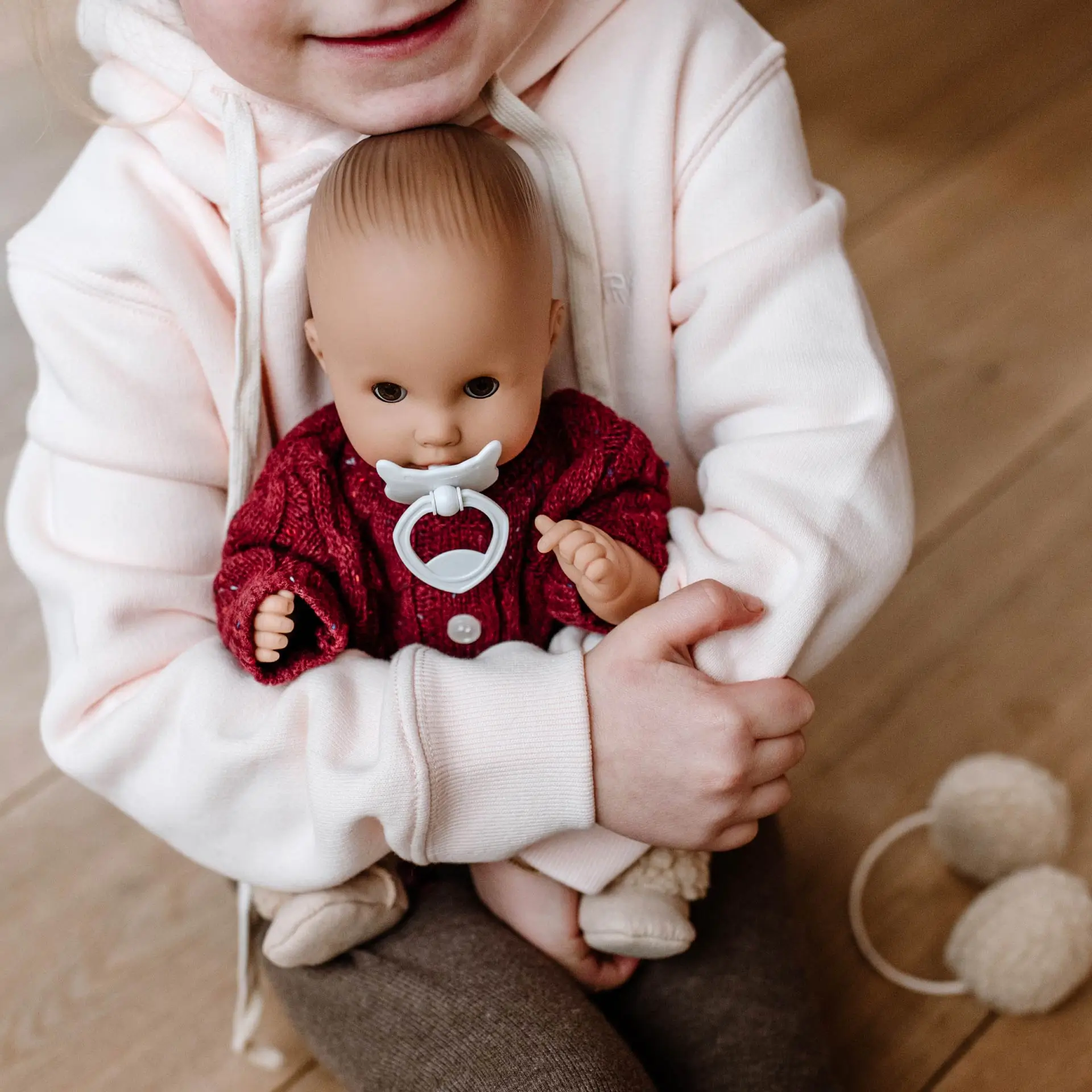 Kind umarmt 33 cm große Babypuppe ohne Haare mit Schnuller  und Schlafaugen