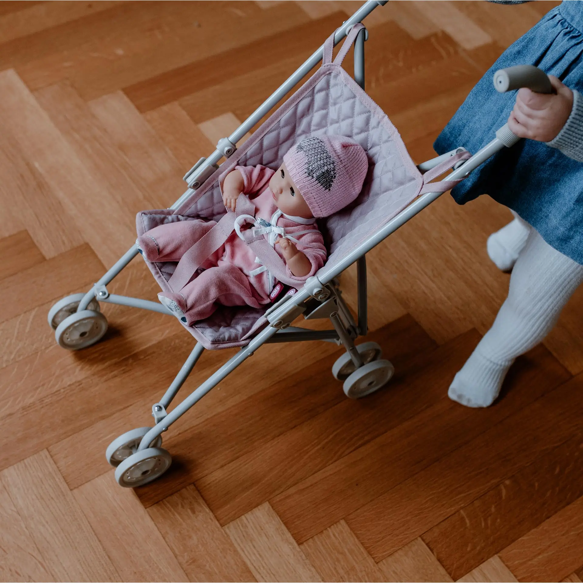 Kind schiebt einen Puppenbuggy mit 33 cm grosser Babypuppe darin