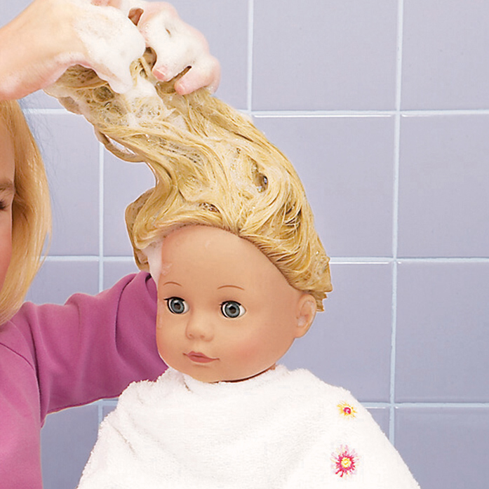 Kind wäscht Stehpuppe ihre blonden Haare