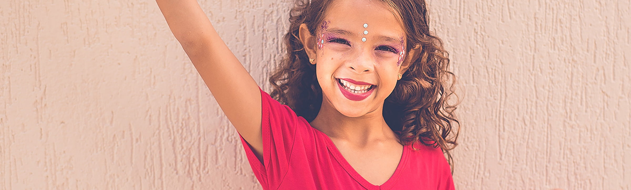 Kind lächelt in die Kamera und hat glitzer schminke im Gesicht