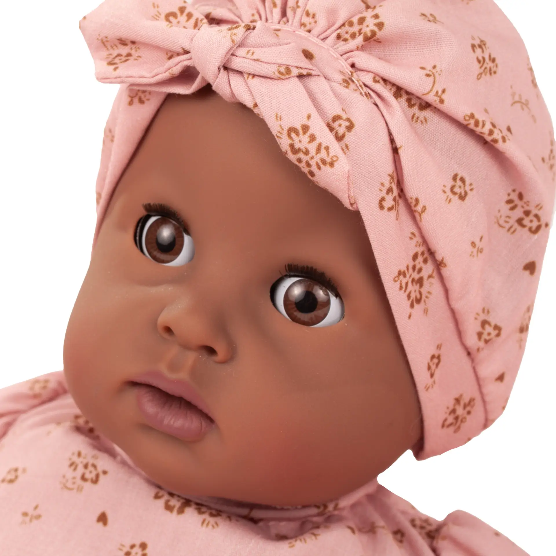 Portrait von brauner Badepuppe Gr. 33 cm mit braunen Schlafaugen ohne Haare und einer Muetze in rosa mit goldfarbenen Bluemchen von Goetz