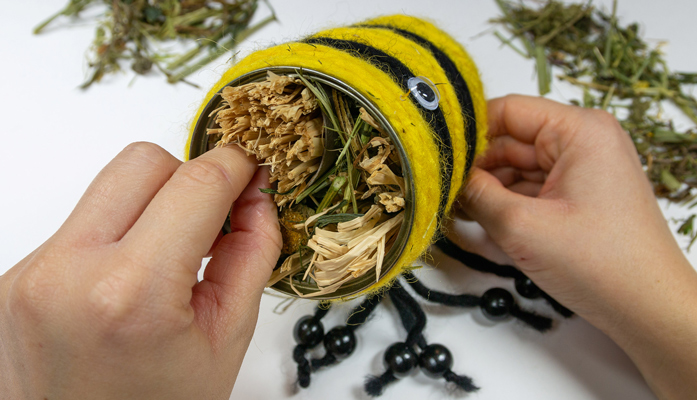 Gelb schwarzes Bienenhaus wird mit Stroh befüllt