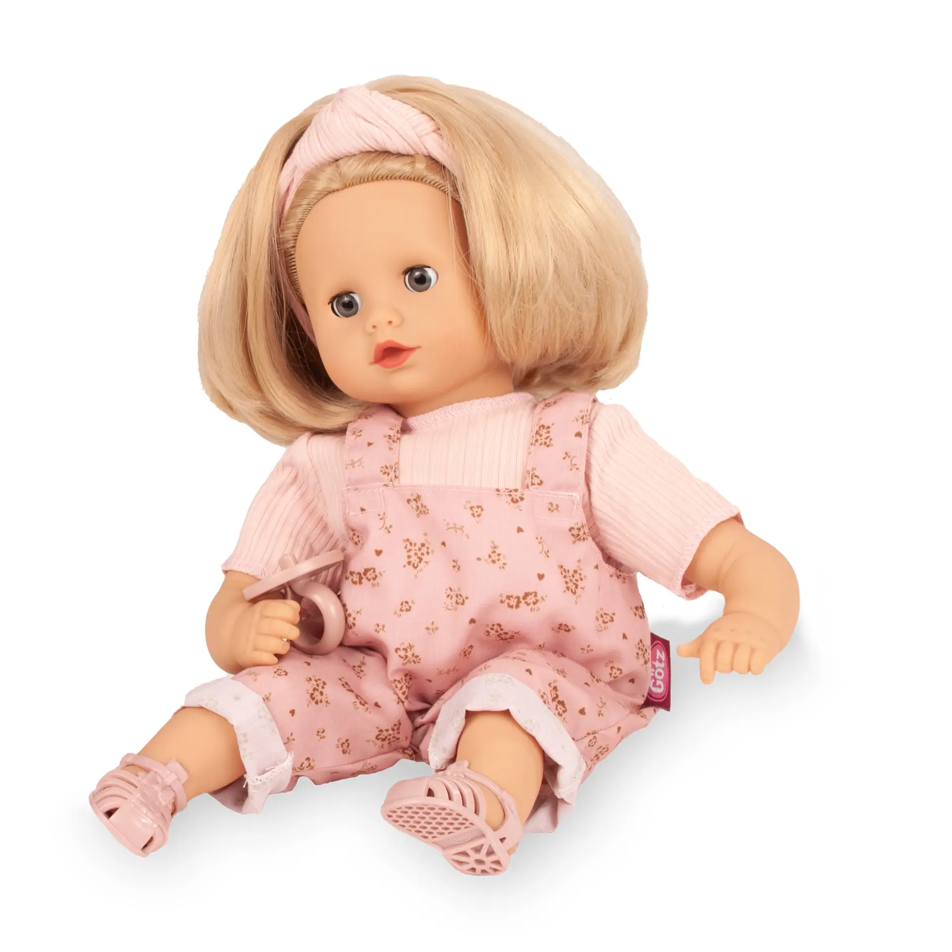 Babypuppe Gr. 30-33 cm mit blondem Haar und blauen Schlafaugen. Gekleidet in rosa Shirt mit rosa Anzug und Badesandalen, einem Haarband und Schnuller von Goetz