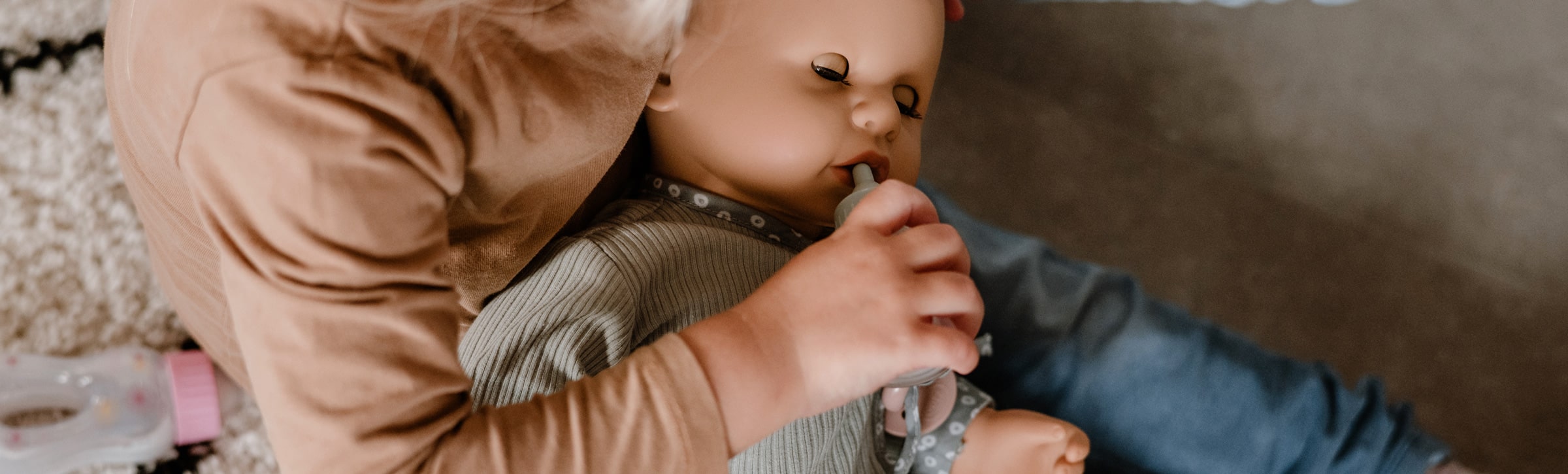 Kind füttert einen goetz Babypuppe, einen Goetz Cookie