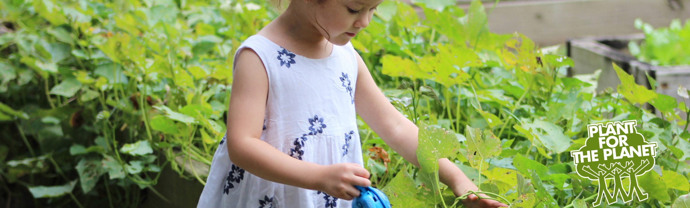 Mädchen im Garten kümmert sich um Blumen und plant for the planat initative Logo mit Goetz Puppen 