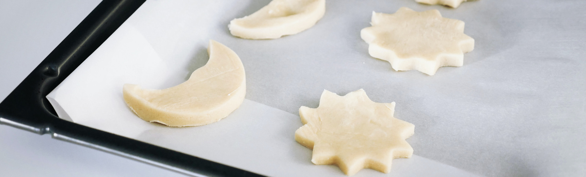 Ausgestochener Plaetzchenteig auf Backpapier auf Backblech