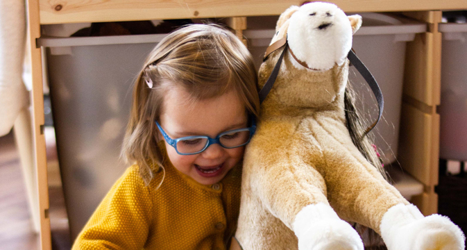 lachendes Kind mit Götz Plüschpferd