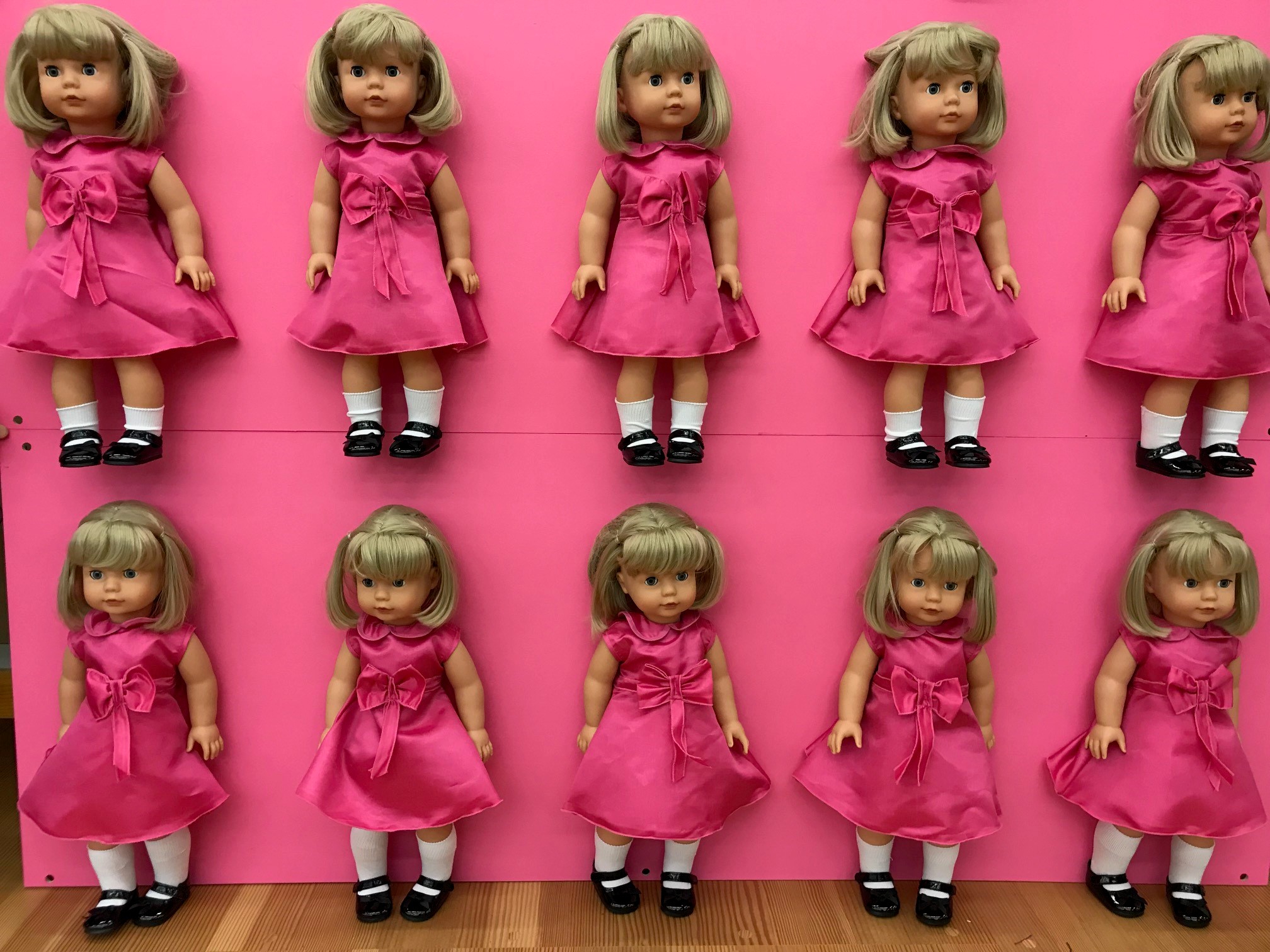 Vorhang auf fuer Goetz Puppen Mehrere blonde Stehpuppen in pinken Kleidern als Teil eines Theaterbuehnenbilds