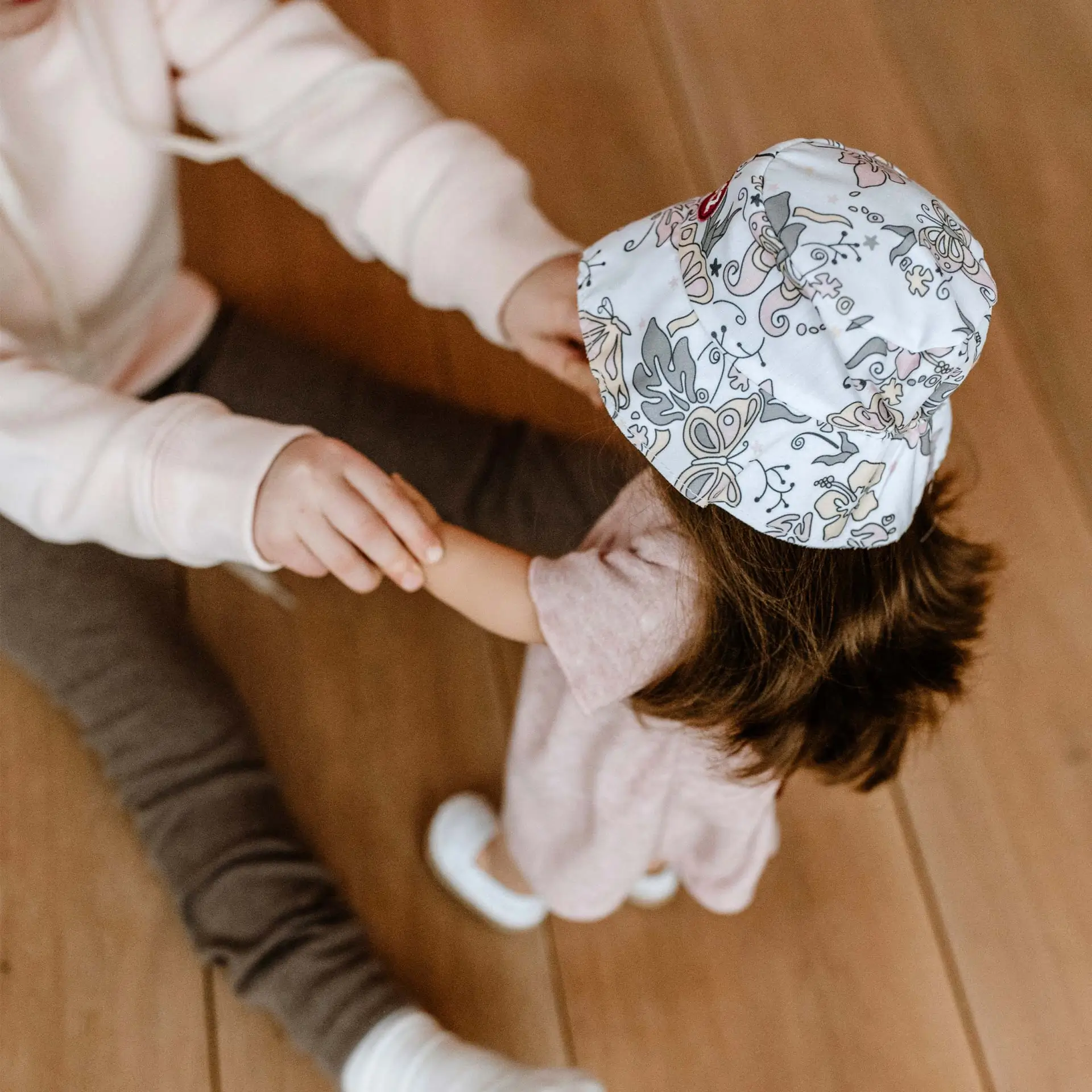 Kind spielt mit einer 46 cm großen Stehpuppe mit braunen Haaren und gemustertem Bucket Hat